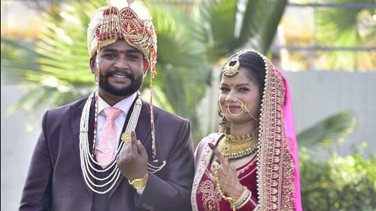 Groom Sunny Chauhan along with her bride Meenakshi Gupta showing inked finger after casting vote at polling booth in Phullanwal in Ludhiana on Sunday. (Gurpreet Singh/HT)