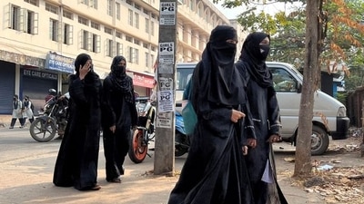 Hijab-wearing students arrive to attend classes as a policewoman stands guard outside a government girls school after the recent hijab ban, in Udupi town in Karnataka (Reuters)