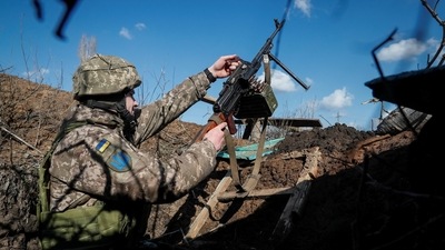 A Ukrainian service member holds a machine gun in a trench at a position on the front line near the village of Travneve in Donetsk region, Ukraine. (REUTERS)