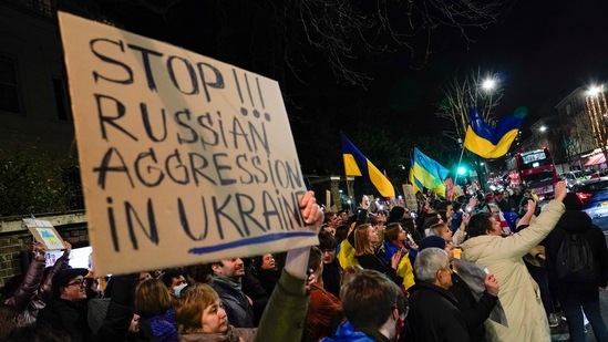 Demonstrators hold placards and flags as they attend a protest outside the Russian Embassy.(AP)