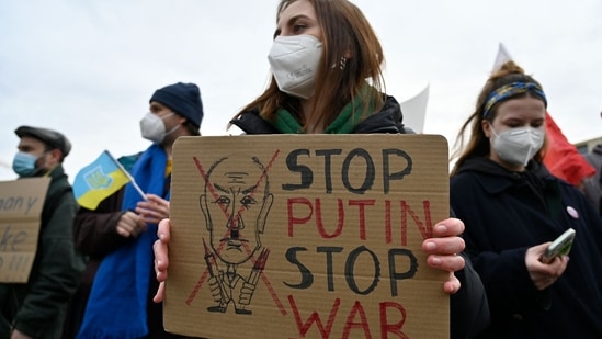 A woman holds a poster asking to "Stop Putin - Stop War" as demonstrators protest against Russia's invasion of Ukraine in front of the Brandenburg Gate in Berlin.(AFP)