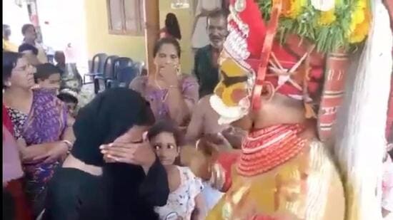 A two-minute video clip of a Theyyam ritual performer consoling a Muslim woman in hijab in northern Kerala has gone viral across social media platforms. (HT photo)