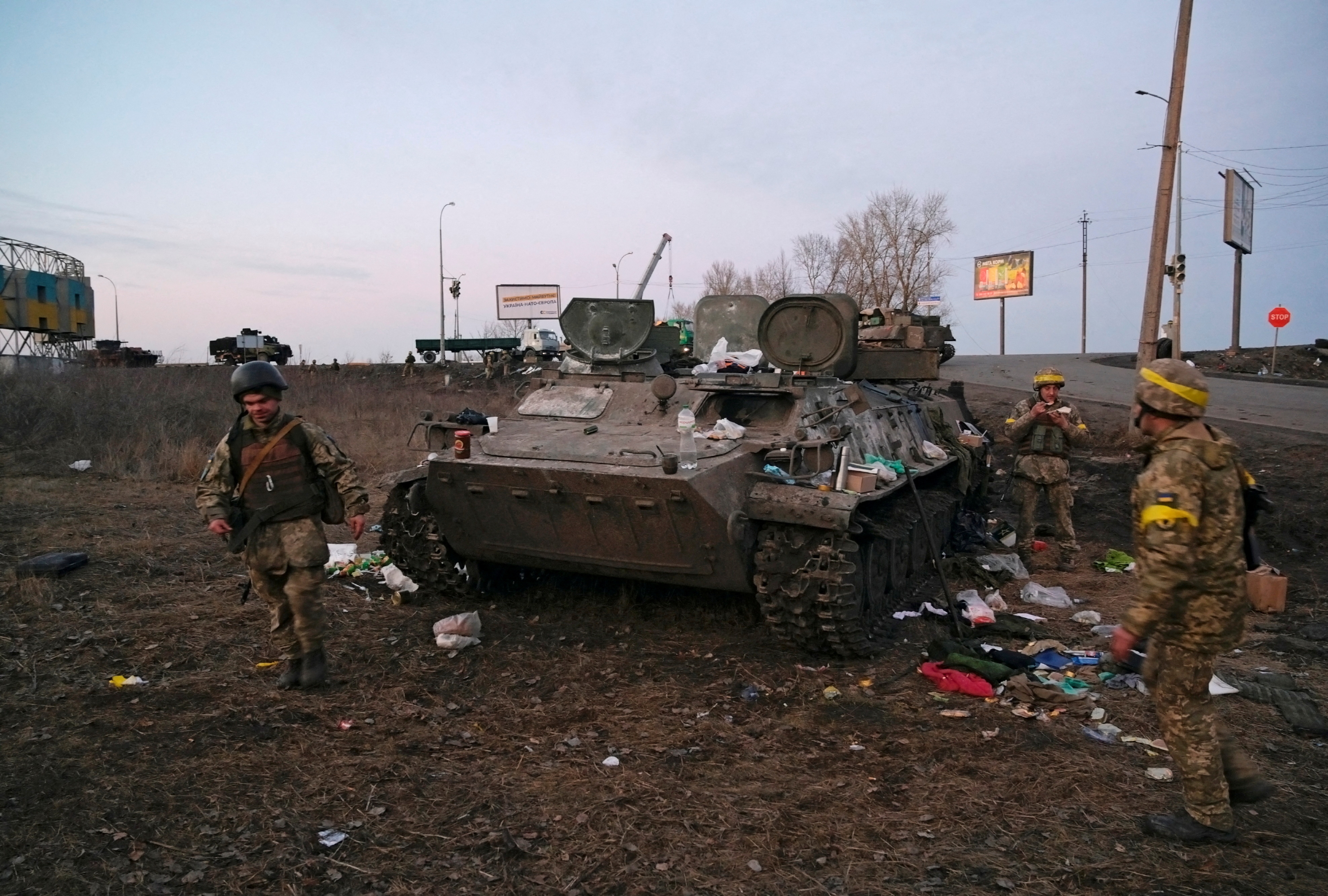 Ukrainian servicemen are seen next to a destroyed armoured vehicle, which they said belongs to the Russian army, outside Kharkiv, Ukraine. (Reuters Photo)