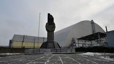 This file photograph taken on December 8, 2020 shows a monument in front of the giant protective dome built over the sarcophagus of the destroyed fourth reactor of Chernobyl nuclear power plant. (AFP)
