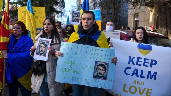 Anti-war protesters hold placards depicting Russian President Vladimir Putin as Adolf Hitler during a demonstration against Russia's invasion of Ukraine in front of the Russian Embassy in Skopje. (AFP)