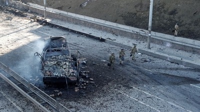 Ukrainian servicemen walk by a damaged vehicle, at the site of fighting with Russian troops, after Russia launched a massive military operation against Ukraine, in Kyiv, Ukraine. (REUTERS)