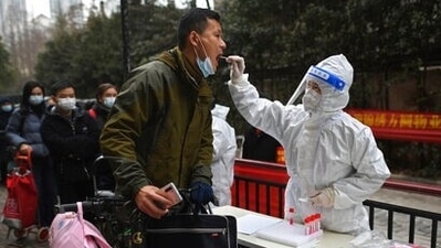 A man holding his bicycle with a school bag on it gets a throat swab during a mass Covid-19 test at a residential compound in Wuhan in central China's Hubei province. (AP) A man holding his bicycle with a school bag on it gets a throat swab during a mass Covid-19 test at a residential compound in Wuhan in central China's Hubei province. (AP)