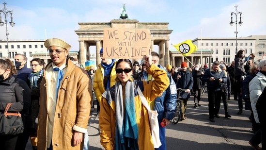 An anti-war protester against the Russian invasion of Ukraine holds a placard at the Brandenburg Gate in Berlin, Germany.(Bloomberg)