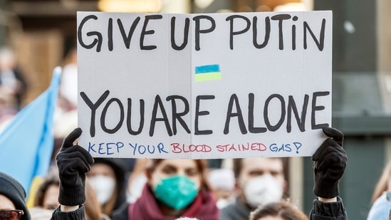 A rally participant holds up a sign reading "Give up Putin, you are alone" during a demonstration at the Rathausmarkt against the Russian attack on Ukraine in Hamburg, Germany, Sunday, February 27, 2022 (AP)