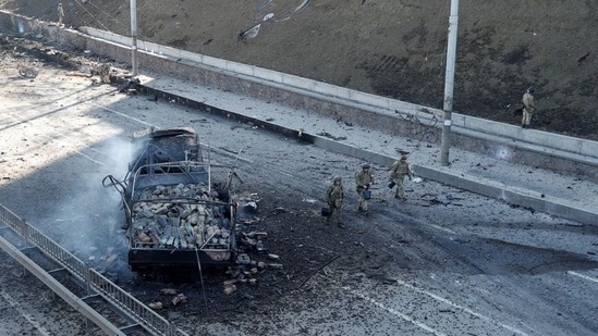 Ukrainian servicemen walk by a damaged vehicle, at the site of a fighting with Russian troops, after Russia launched a massive military operation against Ukraine, in Kyiv, Ukraine, February 26, 2022. (REUTERS/Valentyn Ogirenko)