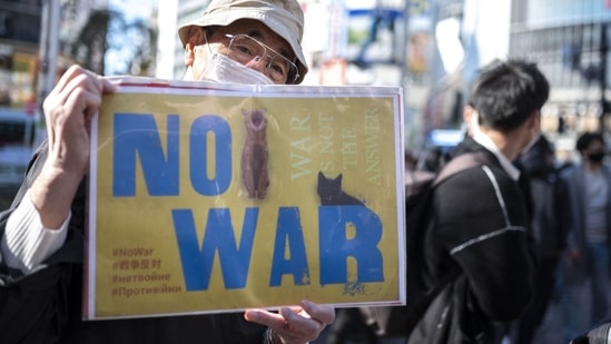 A man holds a placard as people gather at Tokyo's Shibuya area to protest Russia's invasion of Ukraine.(AFP)