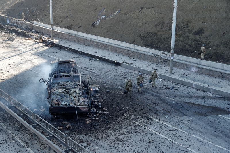 Ukrainian servicemen walk by a damaged vehicle, at the site of a fighting with Russian troops, after Russia launched a massive military operation against Ukraine, in Kyiv, Ukraine, February 26, 2022. (REUTERS/Valentyn Ogirenko)