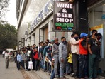 People stand in a queue outside a liquor store as prices of liquor were reduced at New Delhi Railway Station, on Sunday. (ANI Photo) People stand in a queue outside a liquor store as prices of liquor were reduced at New Delhi Railway Station, on Sunday. (ANI Photo)
