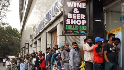 People stand in a queue outside a liquor store as prices of liquor were reduced at New Delhi Railway Station, on Sunday. (ANI Photo) People stand in a queue outside a liquor store as prices of liquor were reduced at New Delhi Railway Station, on Sunday. (ANI Photo)