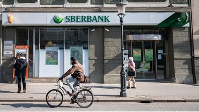 A man cycles past one of the Slovenian branches of the Russian state-owned bank Sberbank, in Ljubljana. (AFP)