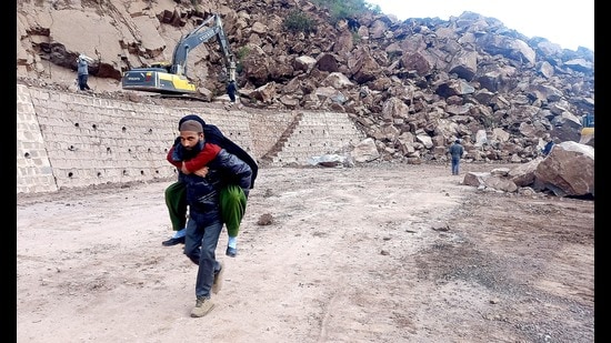 A man carries his ailing wife on his shoulders after a landslide blocked the Jammu–Srinagar National Highway near Samroli in Udhampur on Monday. (ANI Photo)