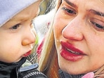 A woman is in tears as she holds her child after feeling from Ukraine and arriving at the border in Kroczowa, Poland (Reuters)