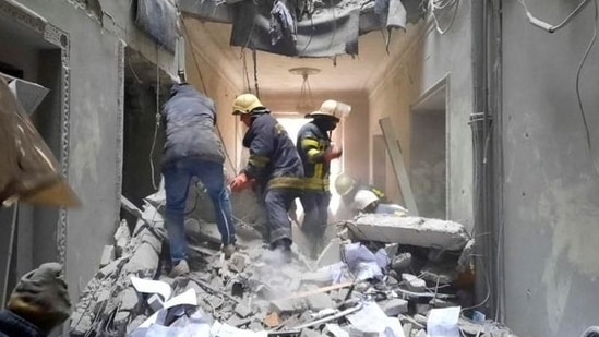 Rescuers seen in a building, which city officials said was damaged by a missile, in central Kharkiv, Ukraine on Tuesday.(REUTERS)