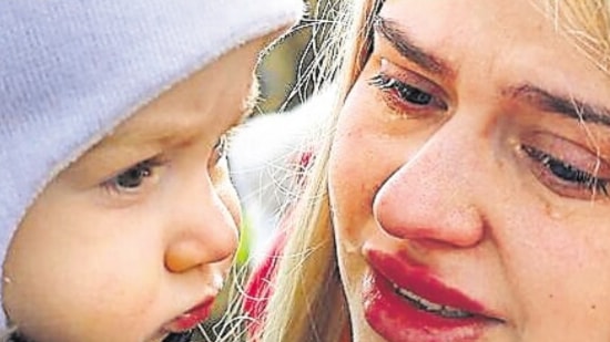 A woman is in tears as she holds her child after feeling from Ukraine and arriving at the border in Kroczowa, Poland (Reuters)