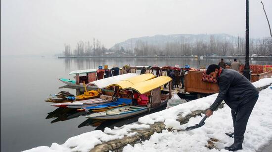 Srinagar: A shikara-walla removes snow from the snow-covered banks of Dal Lake, after sudden heavy snowfall, in Srinagar, Thursday, Feb 24, 2022. (PTI Photo)(PTI02_24_2022_000130B) (PTI)
