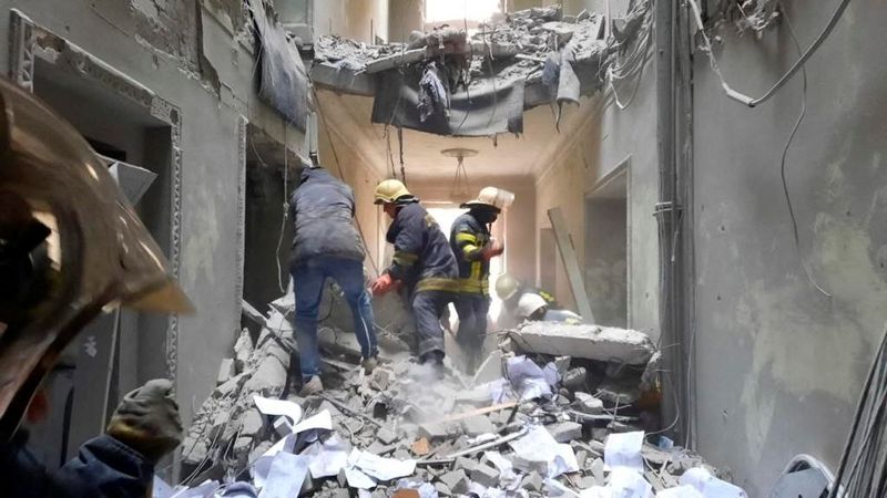 Rescuers seen in a building, which city officials said was damaged by a missile, in central Kharkiv, Ukraine on Tuesday. (REUTERS)