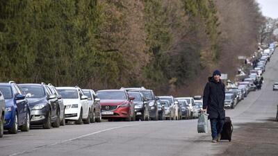A man walking past a long queue of cars at the Shehyni-Medyka border crossing, 82km from Lviv city in west Ukraine, as people tried to flee to Poland on Tuesday. (PTI Photo)