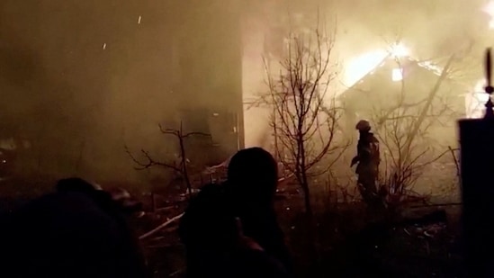 Firefighters walk on debris as a building burns following a Russian strike during Russia's invasion of Ukraine, in Zhytomyr.