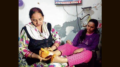 MBBS student Tanushree’s mother applies ointment to her feet that were swollen after long walks to reach the border for evacuation. (HT Photo)