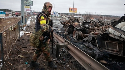 An armed man stands by the remains of a Russian military vehicle in Bucha, close to the capital Kyiv, Ukraine. (AP) An armed man stands by the remains of a Russian military vehicle in Bucha, close to the capital Kyiv, Ukraine. (AP)