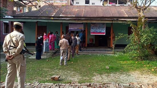 Police personnel stand guard while voters wait to cast their ballot during the first phase of Manipur assembly elections on Monday. (ANI Photo)