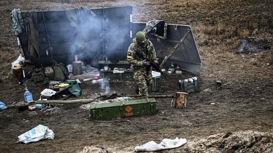 An Ukrainian soldier walks next to a camp fire at a frontline, northeast of Kyiv on March 3, 2022.