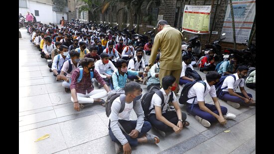 On the first day of HSC exams, a guard is seen checking body temperature of students before they enter the examination hall at MES Bhave High School, on Friday. (Rahul Raut/HT PHOTO)