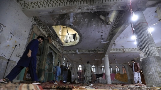 People walk amid the damages at the prayer hall after a bomb blast inside a mosque during Friday prayers in Peshawar, Pakistan, March 4, 2022.(Reuters)