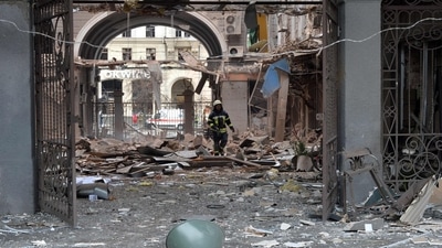 A firefighter walks among damages in a building entrance after the shelling by Russian forces.