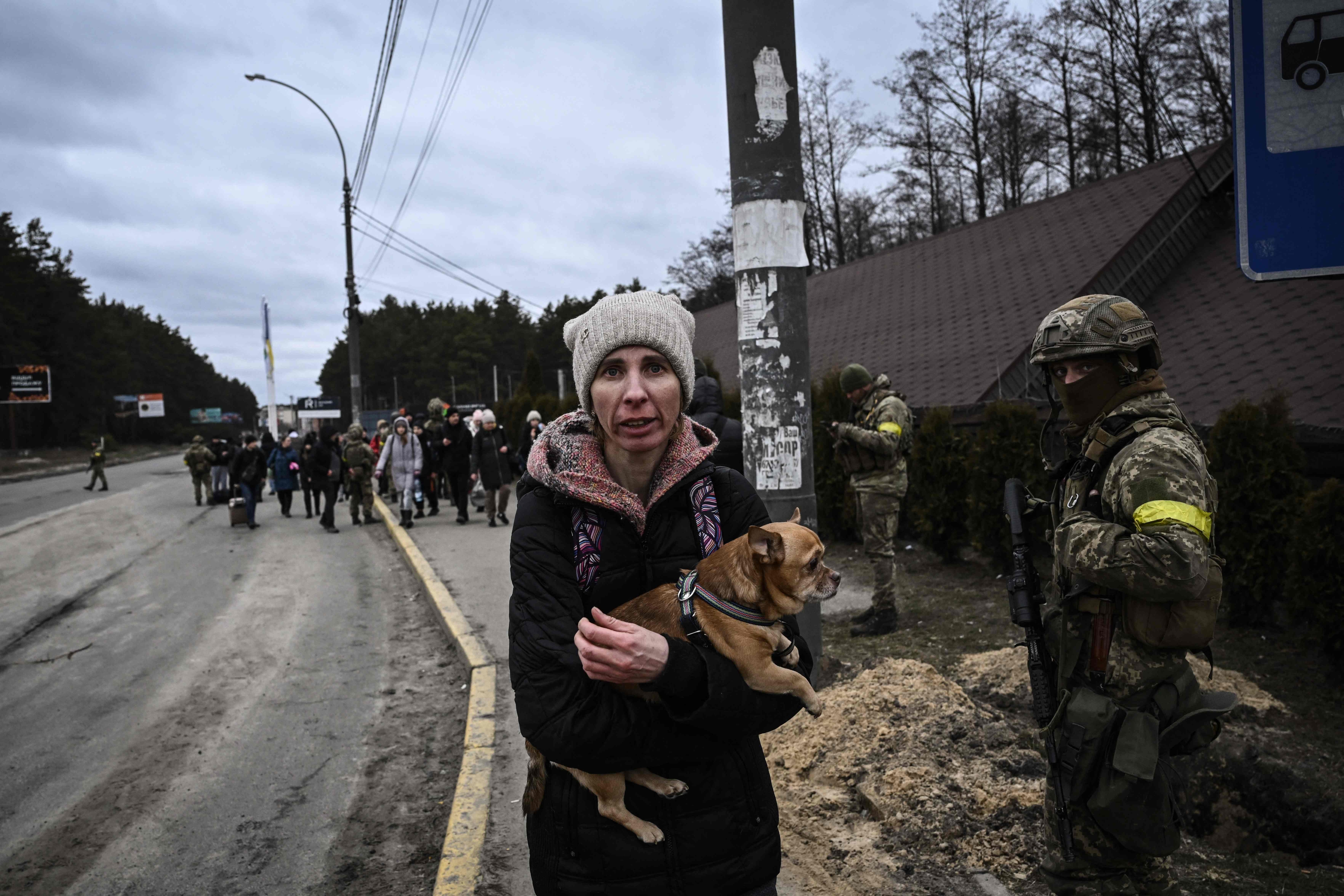 A woman holding her dog reacts as residents evacuate the city of Irpin, northwest of Kyiv, during heavy shelling and bombing on Saturday. (AFP)