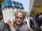 A polling officer carrying an EVM and other election material leaves for his polling booth, at a distribution centre at Pahadiya Mandi, in Varanasi on Sunday. (PTI)