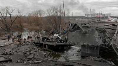 People cross a destroyed bridge as they try to leave the city of Irpin, in the Kyiv region, Ukraine March 5, 2022. (via Reuters)