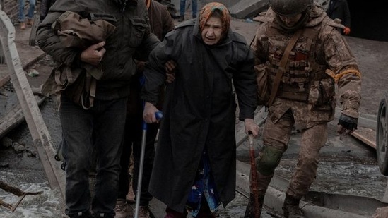 An elderly woman is helped while crossing a destroyed bridge as she tries to leave the city of Irpin, in the Kyiv region.(Agencja Wyborcza.pl via REUTERS)