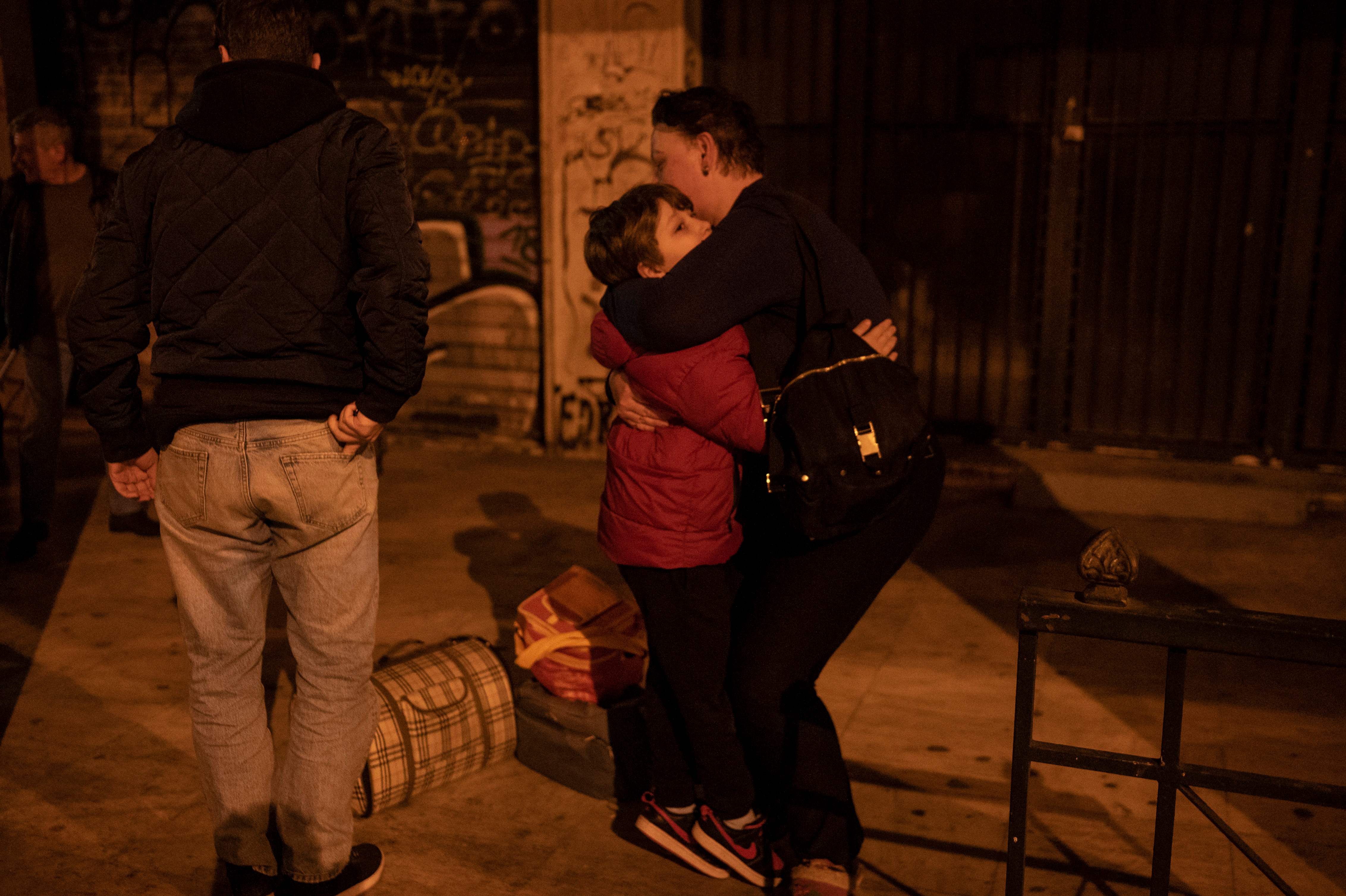 An Ukrainian refugee from Odessa, a port city on the Black Sea, hug as they arrive in Athens by bus, following the Russian invasion of Ukraine on March 6, 2022. (AFP)