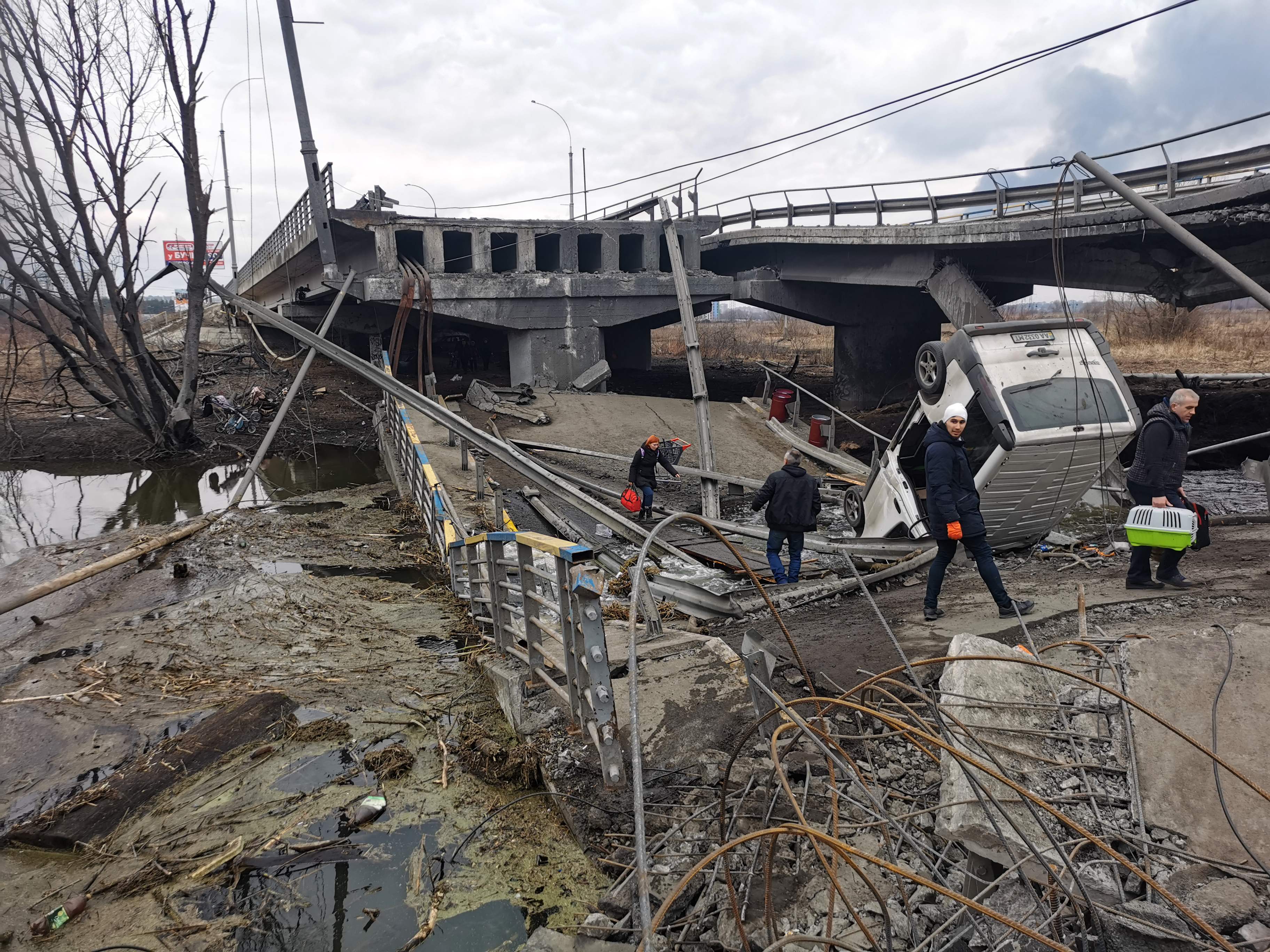 Pedestrians cross a destroyed bridge as they evacuate the city of Irpin, northwest of Kyiv, on Sunday. (AFP) Pedestrians cross a destroyed bridge as they evacuate the city of Irpin, northwest of Kyiv, on Sunday. (AFP)