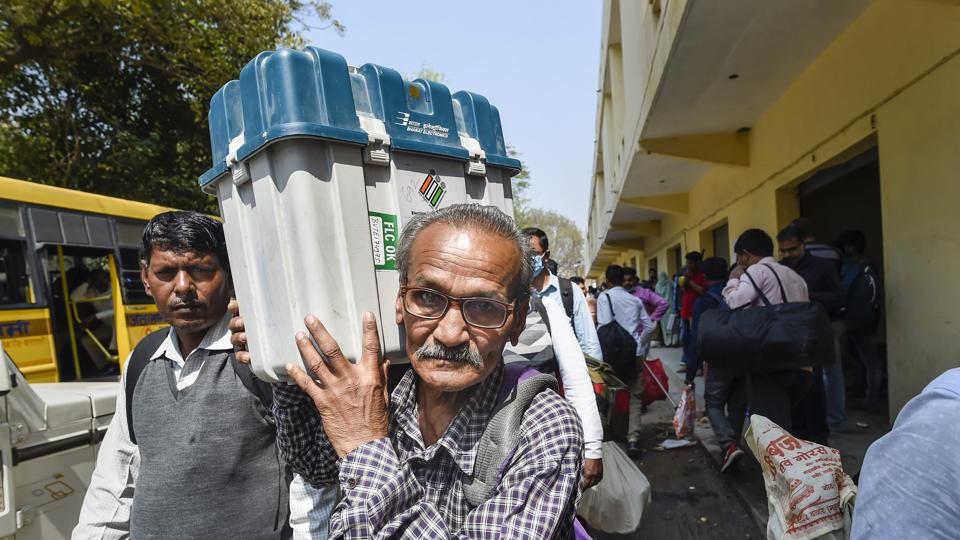 A polling officer carrying an EVM and other election material leaves for his polling booth, at a distribution centre at Pahadiya Mandi, in Varanasi on Sunday. (PTI) A polling officer carrying an EVM and other election material leaves for his polling booth, at a distribution centre at Pahadiya Mandi, in Varanasi on Sunday. (PTI)