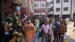 A security personnel stands guard as people queue up to cast their vote in Varanasi on Monday. (MOHD MUQEED/HT PHOTO)
