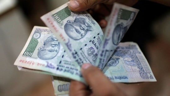 An employee counts Indian rupee currency notes inside a private money exchange office in New Delhi.(REUTERS)