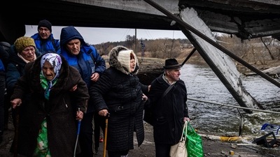 Elderly evacuees are helped to cross a destroyed bridge as they flee the city of Irpin, northwest of Kyiv, (AFP)