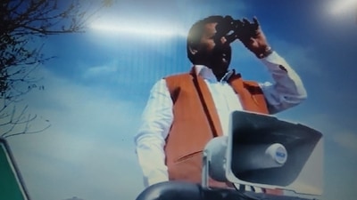 Samajwadi Party candidate from Hastinapur constituency in Meerut district, Yogesh Verma keeps an eye on EVM strong room with binoculars (ANI)