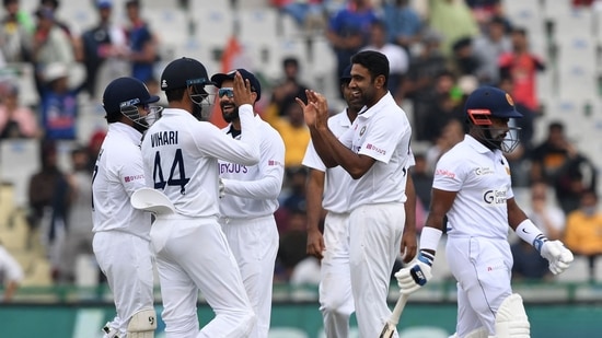 Sri Lanka's Charith Asalanka (R) walks back to the pavilion as India's Ravichandran Ashwin (2R) celebrates with teammates after his dismissal during the third day of the first Test cricket match between India and Sri Lanka at the Punjab Cricket Association Stadium in Mohali on March 6, 2022.