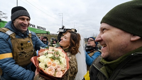 Kyiv mayor Vitali Klitschko congratulates the servicemen of Ukrainian territorial defence, Valery (R) and Lesya (C), with their wedding not far from check-point on Kyiv outskirts. (AFP)