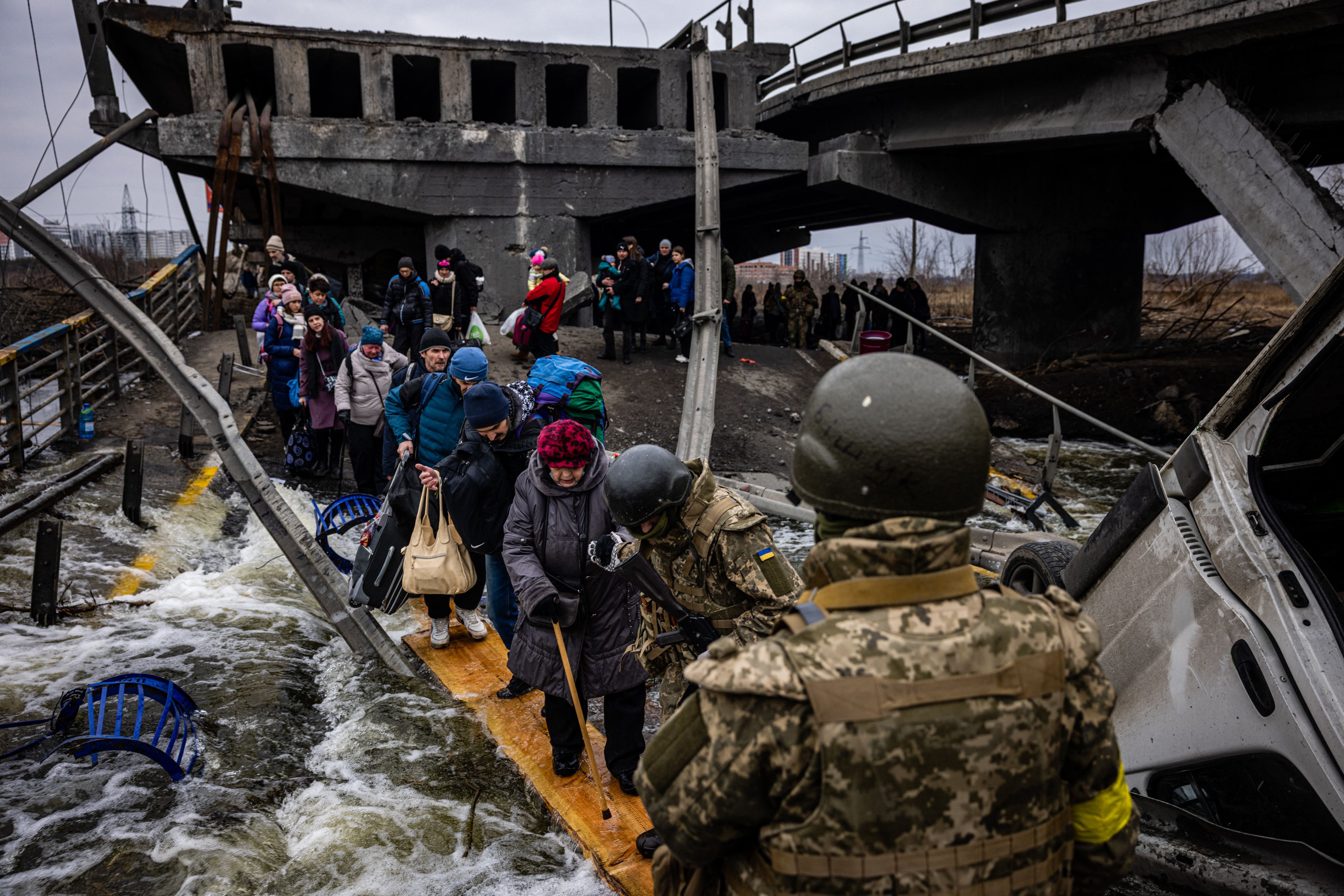 Evacuees cross a destroyed bridge as they flee the city of Irpin, northwest of Kyiv, on March 7, 2022. (AFP) Evacuees cross a destroyed bridge as they flee the city of Irpin, northwest of Kyiv, on March 7, 2022. (AFP)