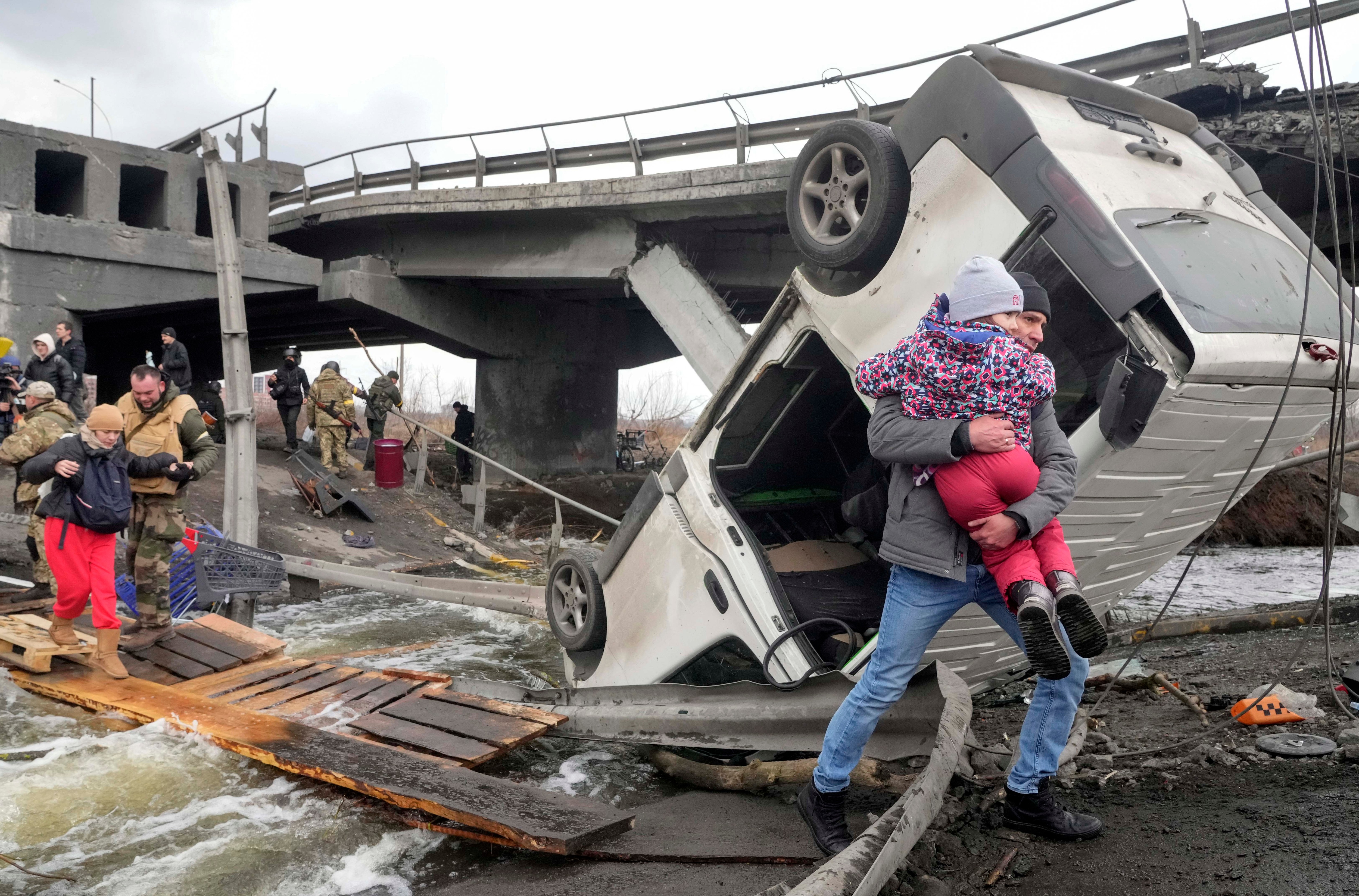People cross an improvised path under a destroyed bridge while fleeing the town of Irpin close to Kyiv. (AP)