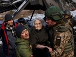 Two men carry a woman as people flee from advancing Russian troops in the town of Irpin outside Kyiv.
